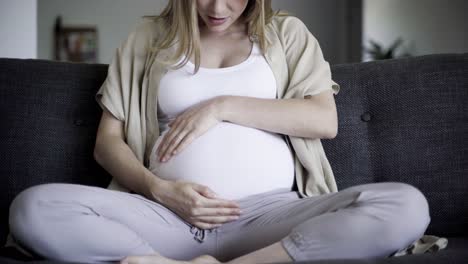 Front-view-of-pregnant-woman-massaging-belly-and-talking